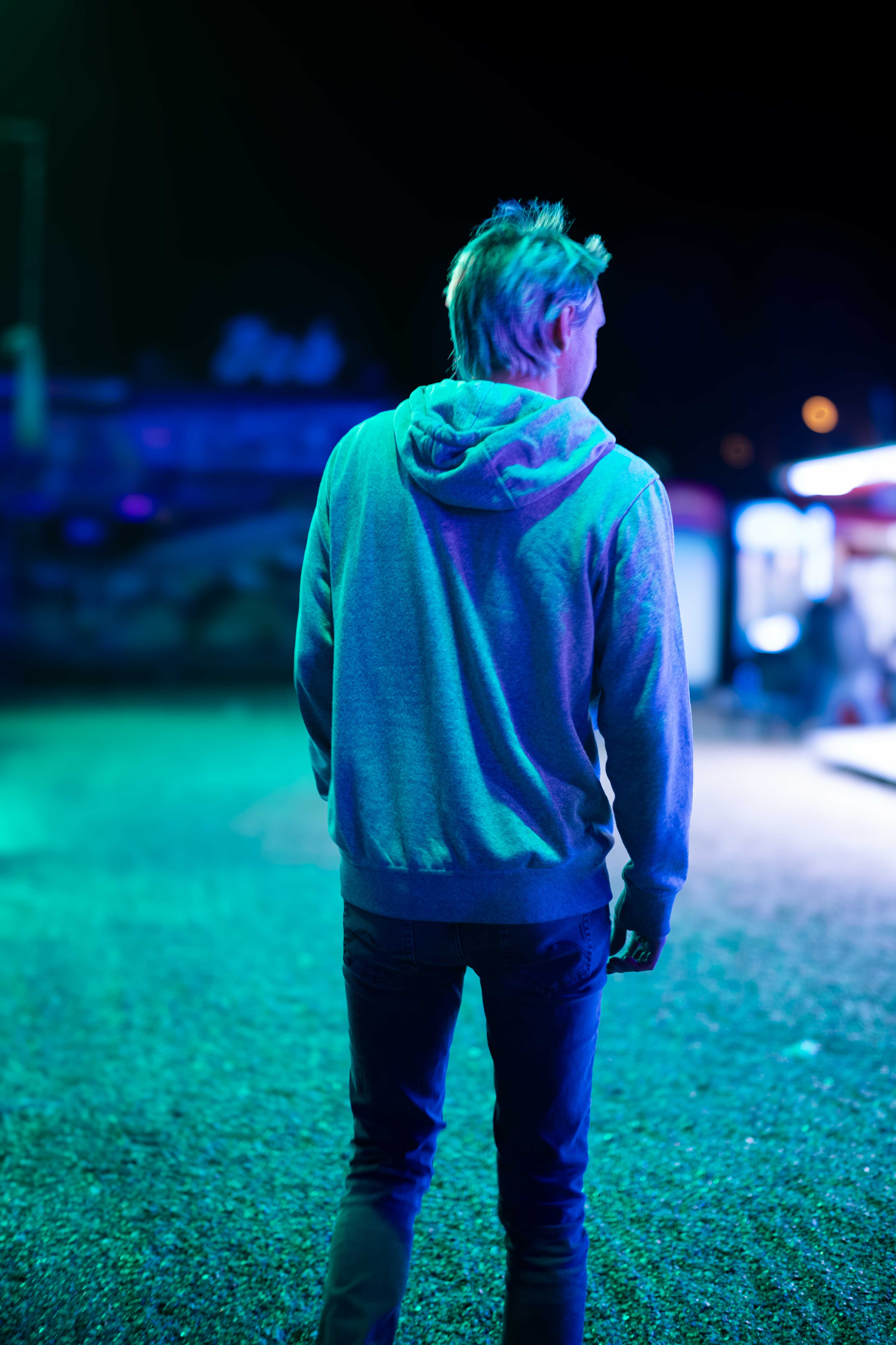 Photo d'un jeune homme de dos marchant dans une fête foraine